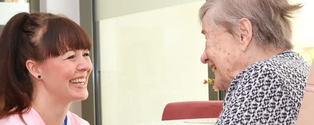 Pflegekraft und Seniorin im Pflegeheim Leipzig im Gespräch – herzliche Betreuung und Fürsorge.